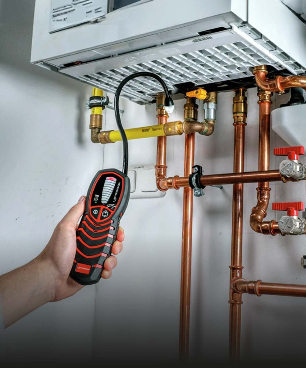 Handwerker misst mit Thermometer an Heizungsrohren