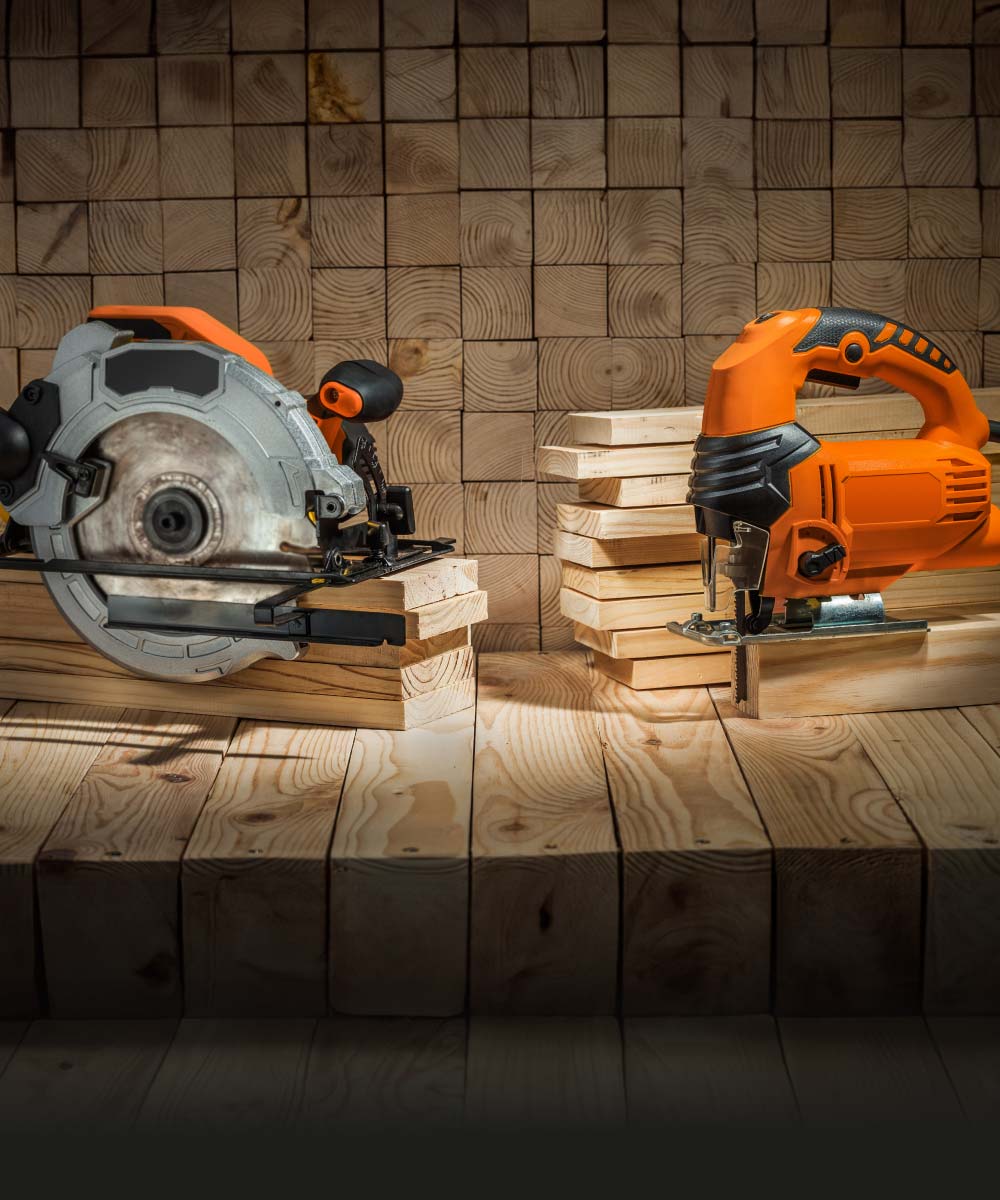 Kreis- und Stichsäge mit Holzstapeln im Hintergrund
