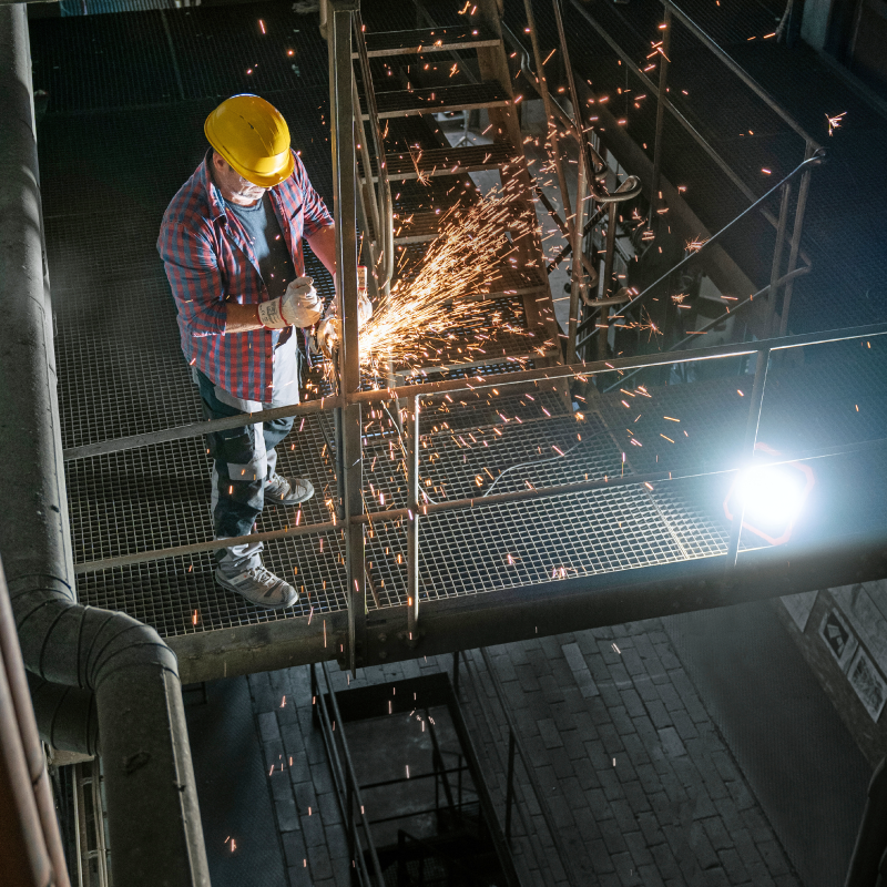 Arbeiter mit Schutzhelm nutzt Winkelschleifer mit Brennenstuhl Beleuchtung