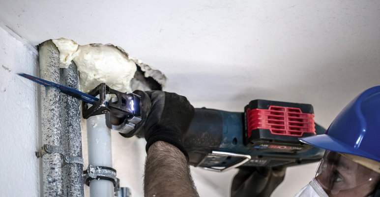 Handwerker verwendet Bosch Akku-Säbelsäge zum Schneiden von Rohren