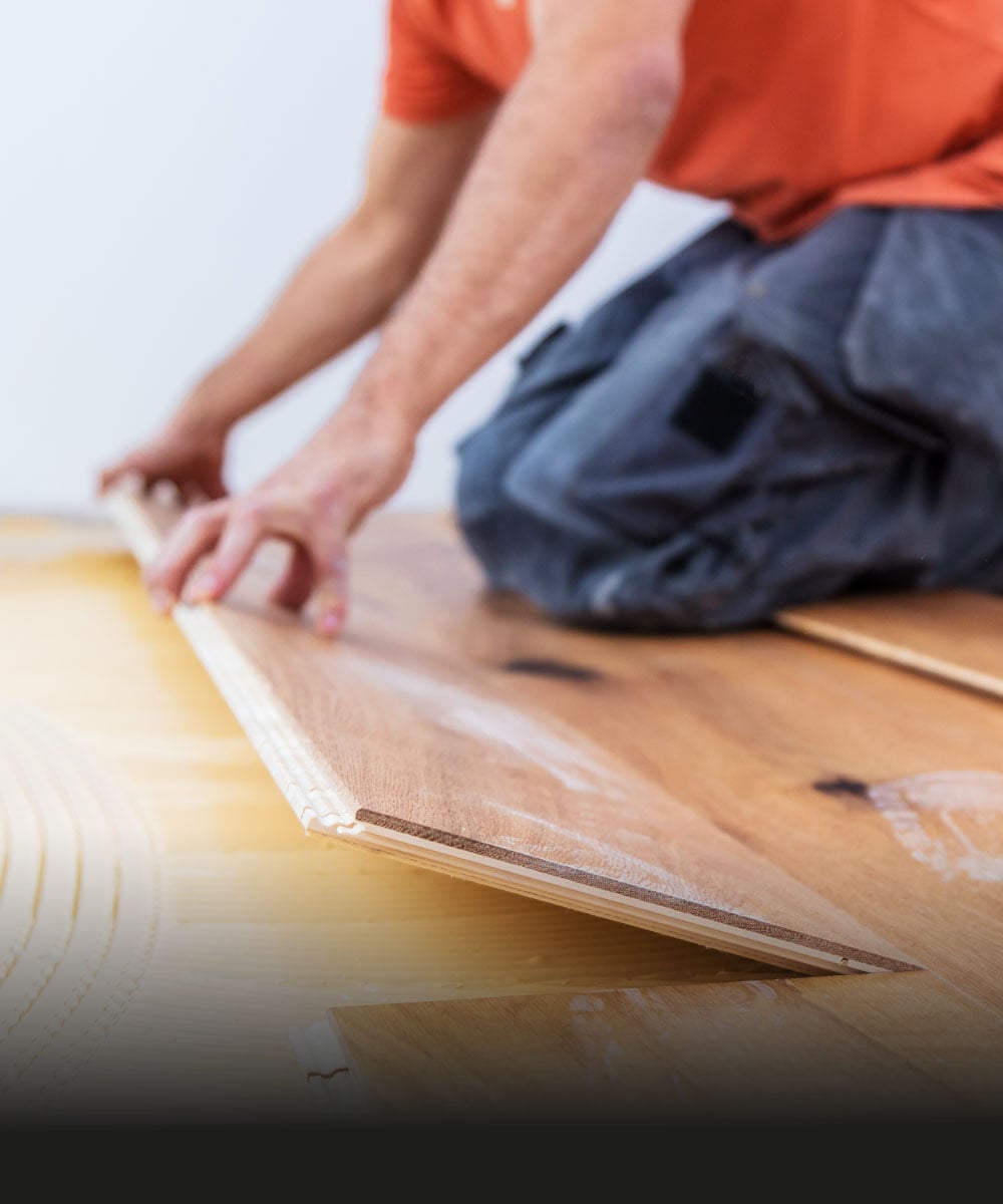 Handwerker verlegt Holzfußboden in einem Raum