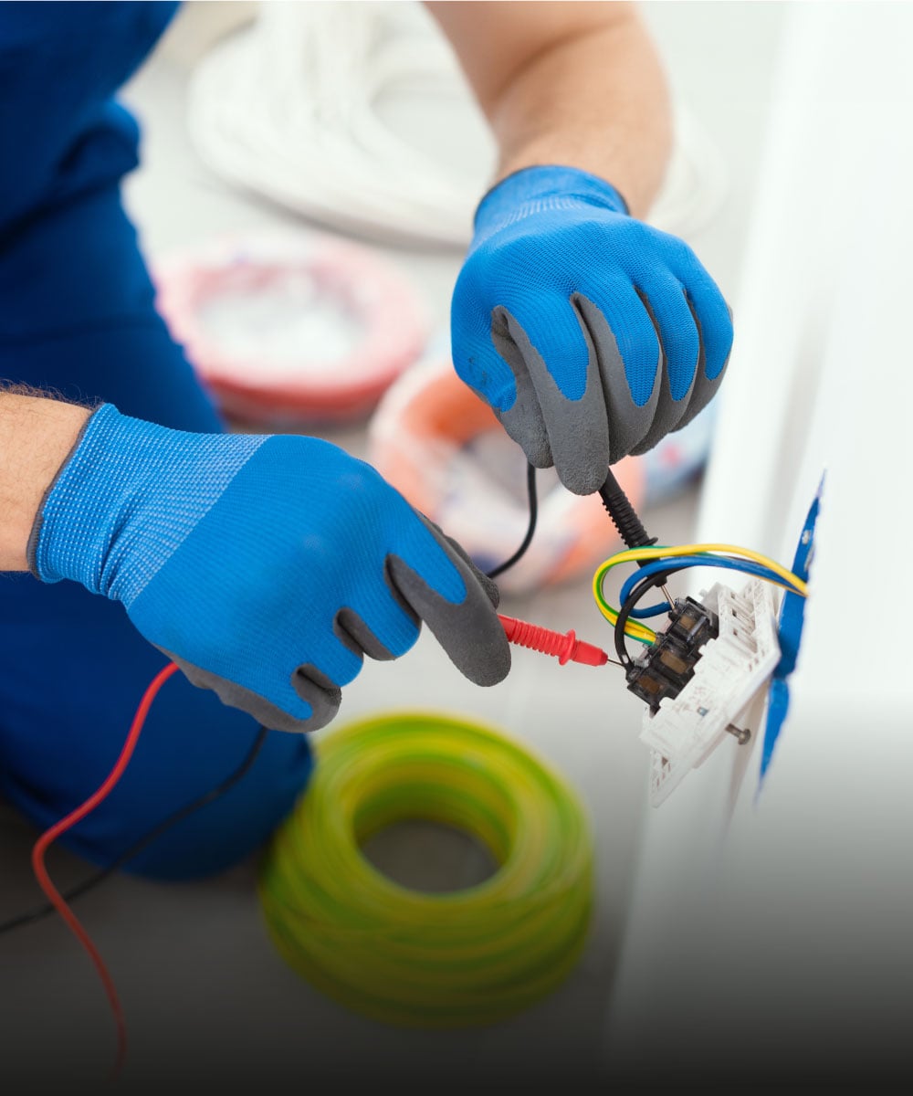 Elektriker mit blauen Handschuhen, der Kabel an einem Anschluss anschließt