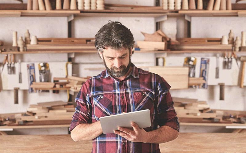 Effiziente Werkstattplanung: Handwerker mit Tablet im Holzlager Handwerker im Holzlager nutzt Tablet zur Planung von Werkstattprojekten